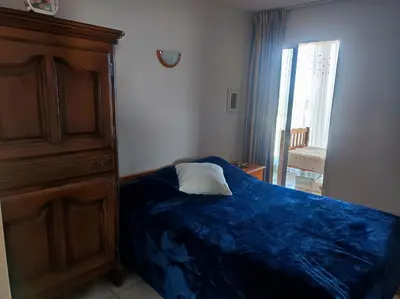 a bedroom with a bed with a blue blanket and a dresser at A 5 mn à pied de la mer, piscine ,tennis, paillote in Cervione