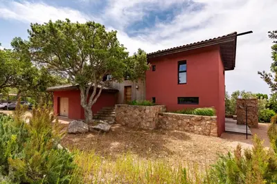 a red house with a tree in front of it at Villa Valle di Corte - Avec piscine et vue mer in Pianottoli-Caldarello