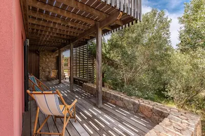 a wooden deck with a chair and a pergola at Villa Valle di Corte - Avec piscine et vue mer in Pianottoli-Caldarello