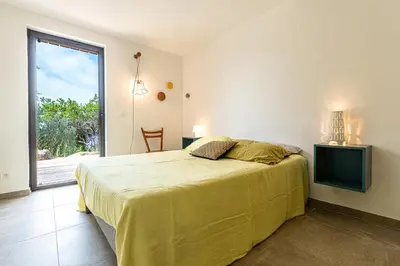 a bedroom with a bed and a sliding glass door at Villa Valle di Corte - Avec piscine et vue mer in Pianottoli-Caldarello