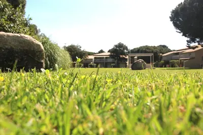 a field of green grass with houses in the background at Studio grande piscine dans résidence hôtelière, proche plage in Lecci