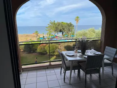 a table and chairs on a balcony with a view of the ocean at Grand studio les pieds dans l'eau in San-Nicolao