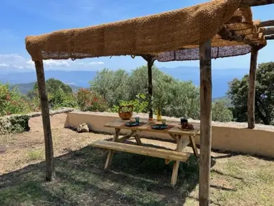 a picnic table under a straw umbrella on a roof at Magnifique Bergerie RONDOLINO vue mer et montagne - U Sognu di Paomia in Cargèse