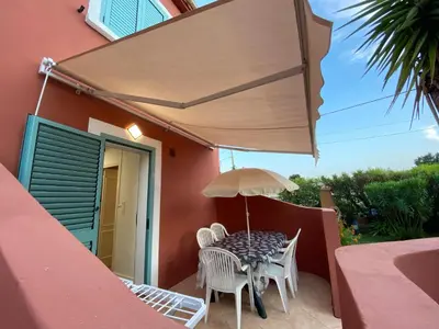 a table and chairs under an umbrella on a patio at Résidence LO MONACO Haut de villa, Appartements et Studios in San-Nicolao