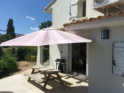 a picnic table with a large pink umbrella on a patio at Appartement Marina di Fiori by Intendance Excellency in Porto-Vecchio
