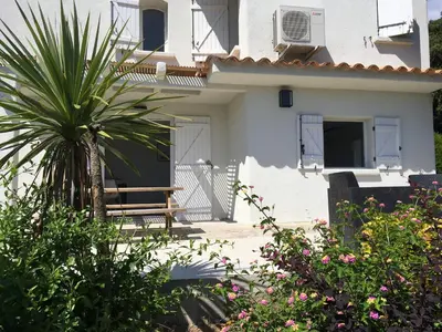 a bench in front of a white house with a palm tree at Appartement Marina di Fiori by Intendance Excellency in Porto-Vecchio