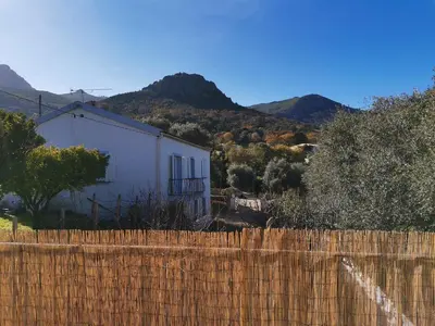 a fence in front of a white building with mountains in the background at Rez Haut de villa à Calenzana in Calenzana