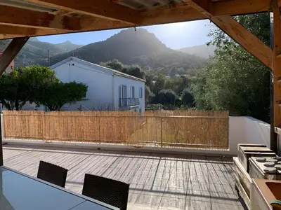 a patio with a wooden fence and a building at Rez Haut de villa à Calenzana in Calenzana