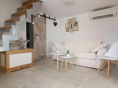 a living room with a white couch and a staircase at Maison de charme proche Bastia in Prunelli-di-Casacconi