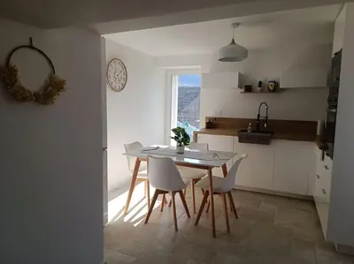 a kitchen with a table and chairs and a window at Maison de charme proche Bastia in Prunelli-di-Casacconi