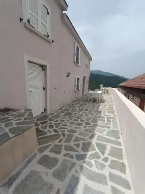 a building with a stone walkway next to a building at Maison de charme proche Bastia in Prunelli-di-Casacconi