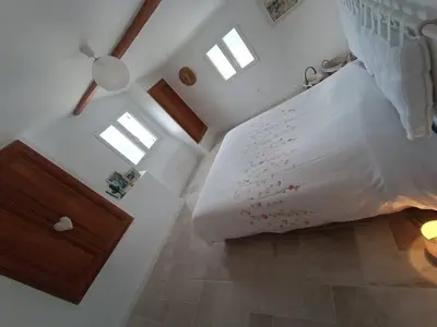a bedroom with a bed with white sheets and windows at Maison de charme proche Bastia in Prunelli-di-Casacconi