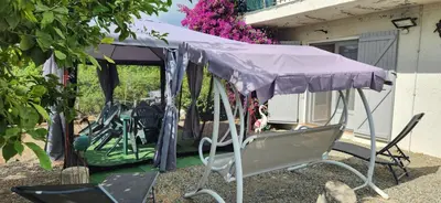 a purple canopy on a patio with chairs under it at Charmant T3 en rez de jardin d'une villa in Ghisonaccia