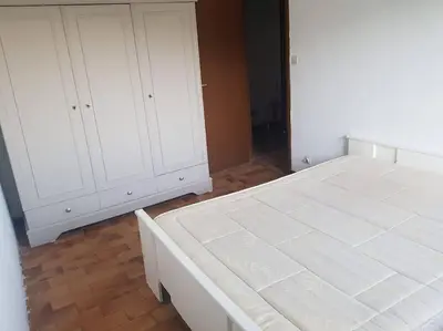 a bedroom with a white bed and white cabinets at Charmant T3 en rez de jardin d'une villa in Ghisonaccia