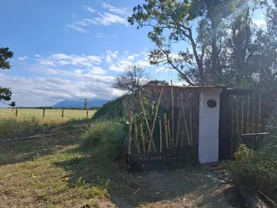 a out house in a field next to a fence at Caravane amy on the beach in Lucciana