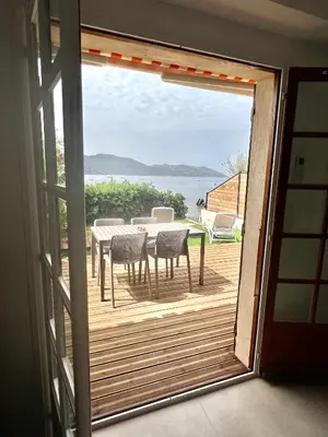 a sliding glass door leading to a deck with a table and chairs at Appartement 2-4 pers, ACCES DIRECT MER in Casaglione