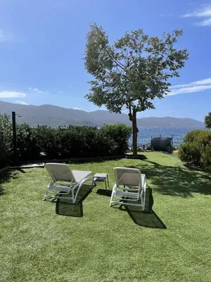two white chairs sitting in the grass with a tree at Accès mer, appartement 2-4 pers sur plage in Casaglione