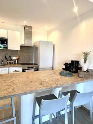 a kitchen with a counter with white appliances and white chairs at Accès mer, appartement 2-4 pers sur plage in Casaglione