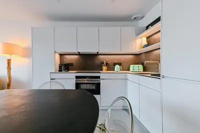 a kitchen with white cabinets and a black table at T2 LUXE Pieds dans l'eau Porticcio in Grosseto-Prugna