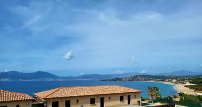 a view of a body of water with a house and mountains at Appartement de standing bord de mer in Pietrosella