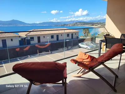a balcony with two chairs and a view of the ocean at Appartement de standing bord de mer in Pietrosella