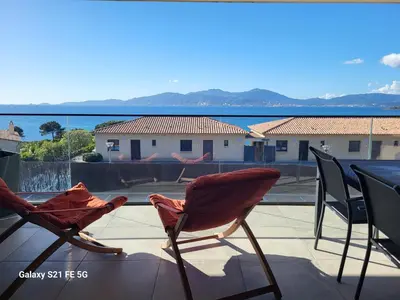 two chairs sitting on a balcony with a view of the ocean at Appartement de standing bord de mer in Pietrosella