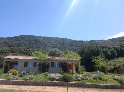a small house with a mountain in the background at Residence Cucunacciu in Cargèse