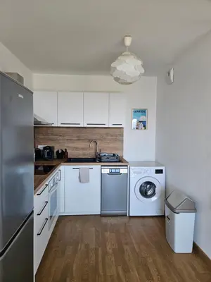 a kitchen with white cabinets and a washer and dryer at Appartement terrasse spacieuse, vue mer & clim in Ajaccio