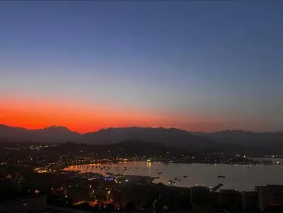 a view of a city and a lake at sunset at Appartement terrasse spacieuse, vue mer & clim in Ajaccio