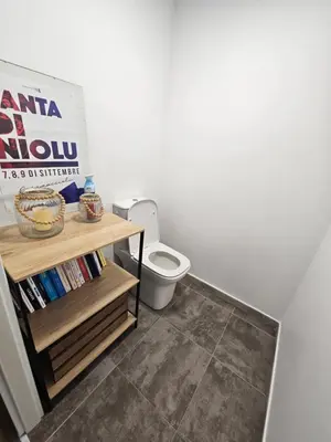 a bathroom with a toilet and a book shelf at Appartement terrasse spacieuse, vue mer & clim in Ajaccio