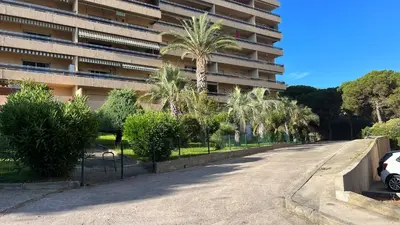 an empty street in front of a building with palm trees at Le Rocher Des Sanguinaires in Ajaccio
