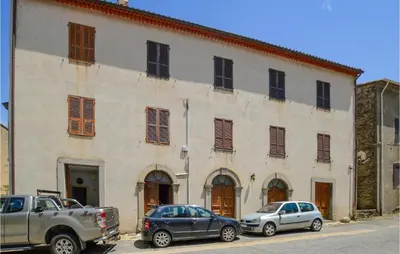 two cars parked in front of a large building at 1 Bedroom Amazing Apartment In Ghisoni in Ghisoni