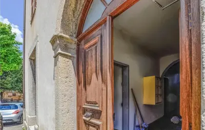 an open wooden door on a building with a car at 1 Bedroom Amazing Apartment In Ghisoni in Ghisoni