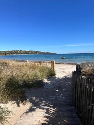 a sandy beach with a wooden fence and the ocean at La poudrière in Figari