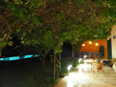 a patio with a table and chairs under trees at night at MAMMONA in Bonifacio