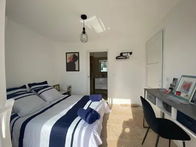 a white bedroom with a bed and a desk at Villa Vittoria in Ghisonaccia