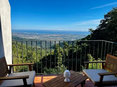a balcony with a table and chairs and a view at Gîtes la fontaine corse vue panoramique in Loreto-di-Casinca