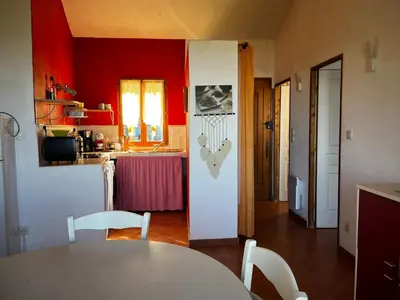 a kitchen with red walls and a white table and chairs at Gîtes la fontaine corse vue panoramique in Loreto-di-Casinca