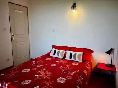 a bedroom with a red bed with three pillows at Gîtes la fontaine corse vue panoramique in Loreto-di-Casinca