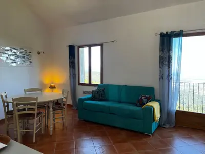 a living room with a blue couch and a table at Gîtes la fontaine corse vue panoramique in Loreto-di-Casinca