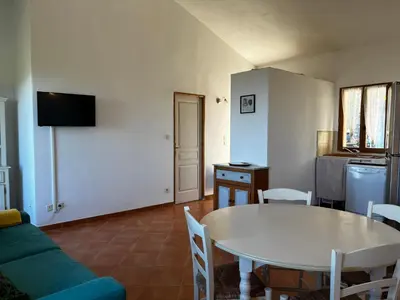 a living room with a table and a kitchen at Gîtes la fontaine corse vue panoramique in Loreto-di-Casinca