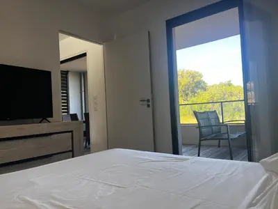 a bedroom with a bed and a television and a balcony at T2 Porticcio neuf in Porticcio