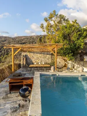 a pool with a wooden pergola and a table and chairs at A Macina in Porri