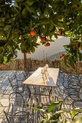 a wooden table and chairs under an orange tree at A Macina in Porri