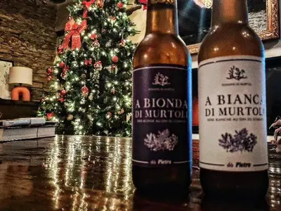 two bottles of beer sitting on a table with a christmas tree at A Macina in Porri