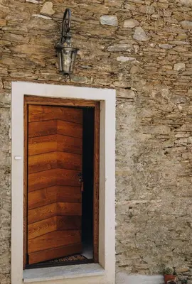 a wooden door in a stone building with a brick wall at A Macina in Porri