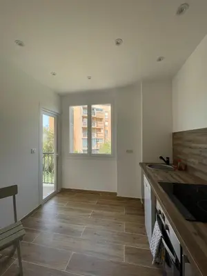 a kitchen with white walls and a wooden floor at Appartement T3 neuf centre ville in Ajaccio