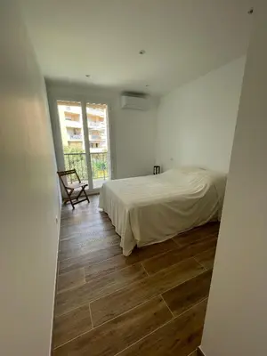 a bedroom with a bed and a wooden floor at Appartement T3 neuf centre ville in Ajaccio