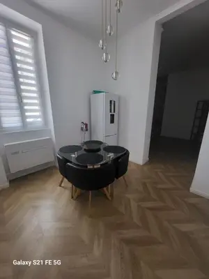 a dining room with a black table and a refrigerator at Grand T2 Cours Napoleon B in Ajaccio