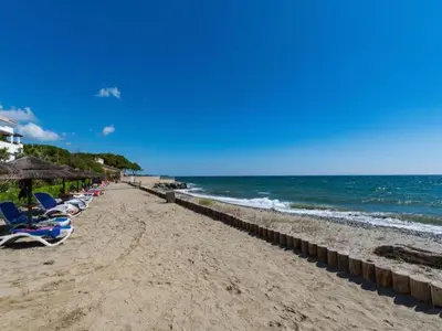 a beach with chairs and umbrellas and the ocean at Vacances en Corse in San-Nicolao